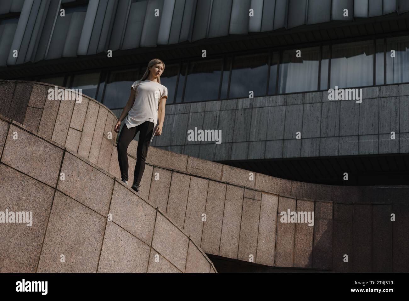 Ritratto di una giovane donna sportiva del parkour. Atleta freeruning in piedi sul tetto. Foto Stock