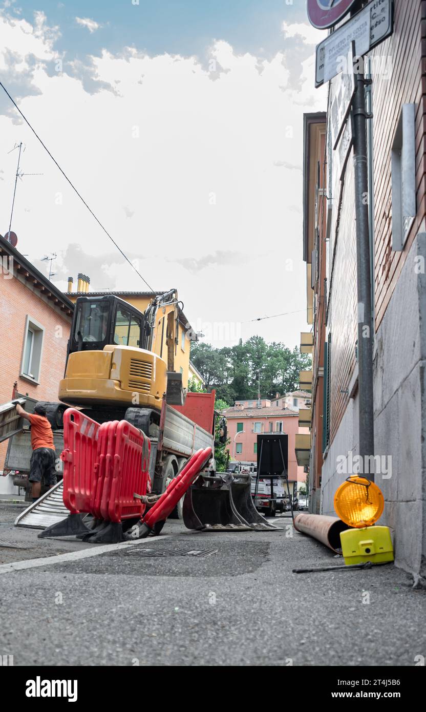 Area di costruzione con operatori che utilizzano barriera, escavatore e terreno di lavoro Foto Stock