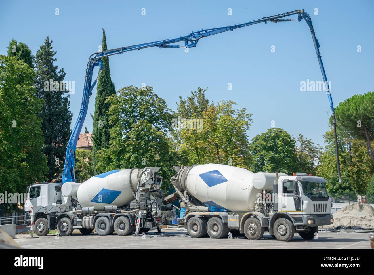 Coppia di carrelli per cemento con impianti idraulici estesi che versano cemento Foto Stock