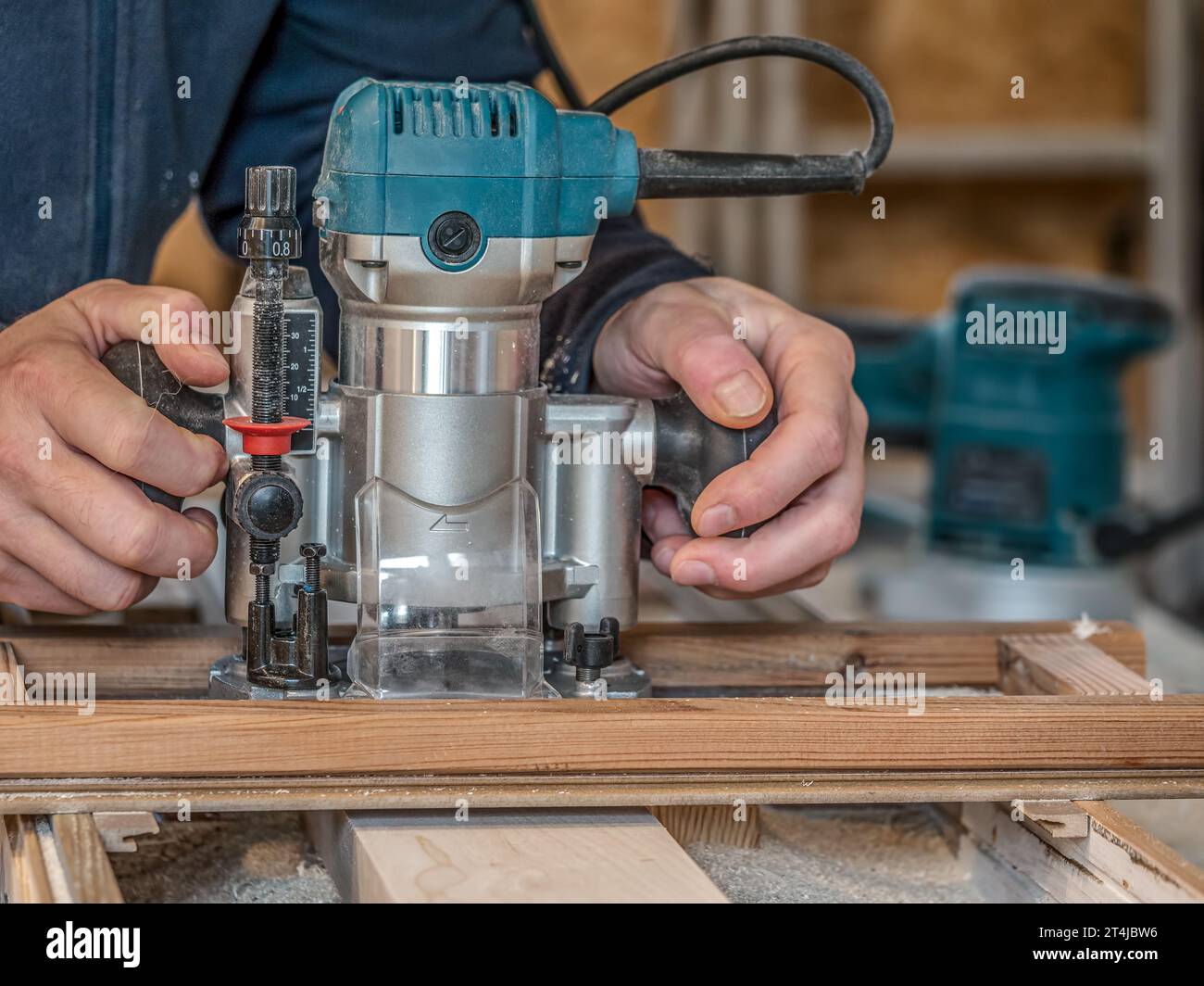 Carpentiere che plana una tavola con una fresa utilizzando una maschera Foto Stock