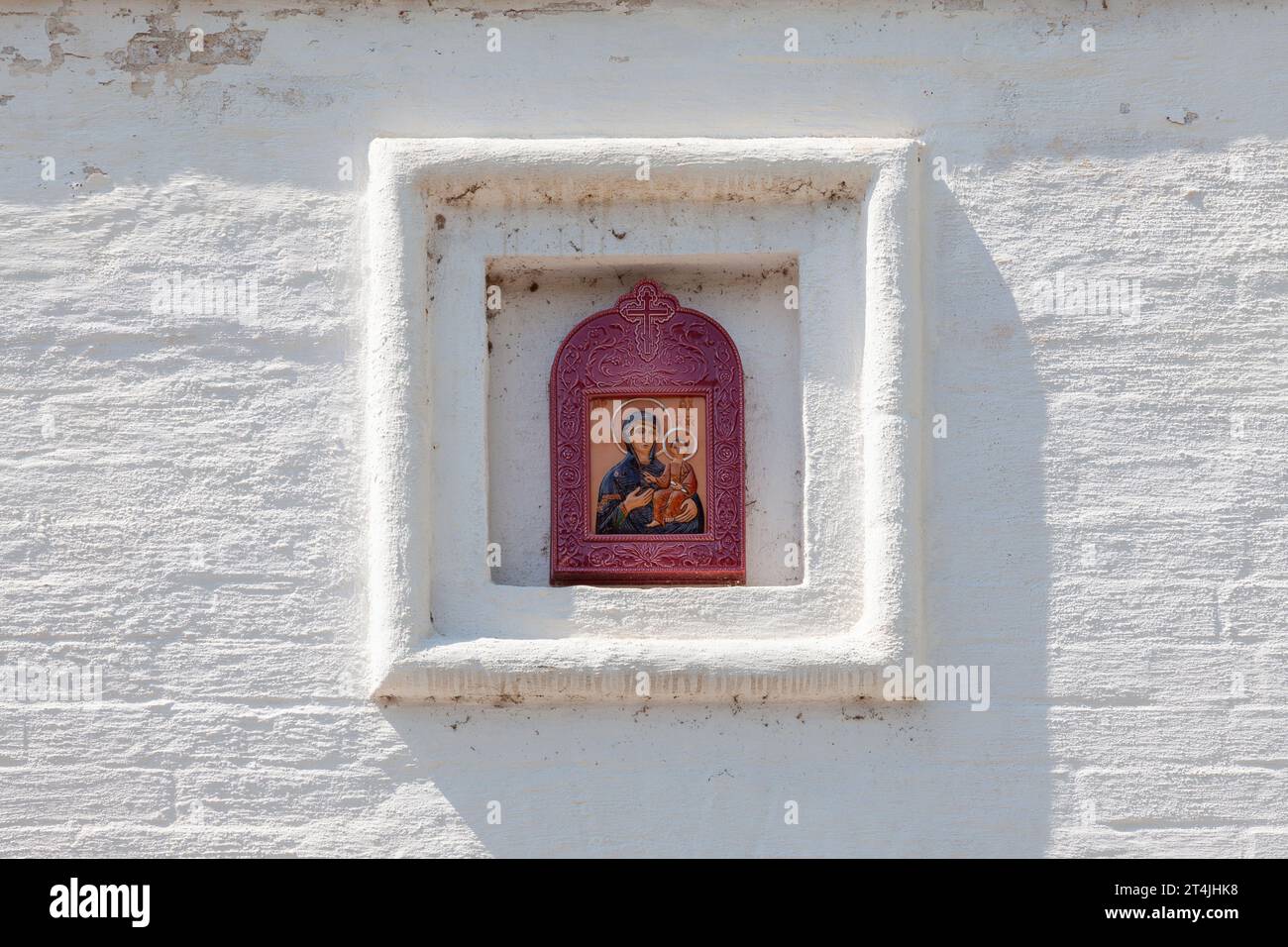 Parete bianca in mattoni di una chiesa ortodossa con un'icona in ceramica della Vergine. Foto Stock