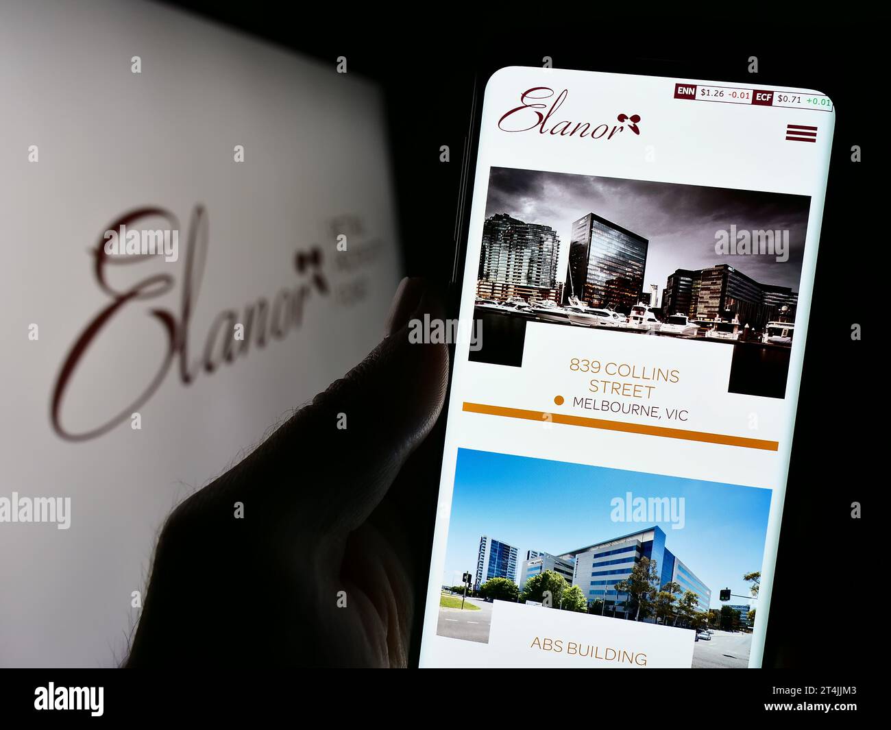 Persona che possiede uno smartphone con la pagina Web dell'azienda australiana Elanor Commercial Property Fund davanti al logo. Concentrarsi sul centro del display del telefono. Foto Stock