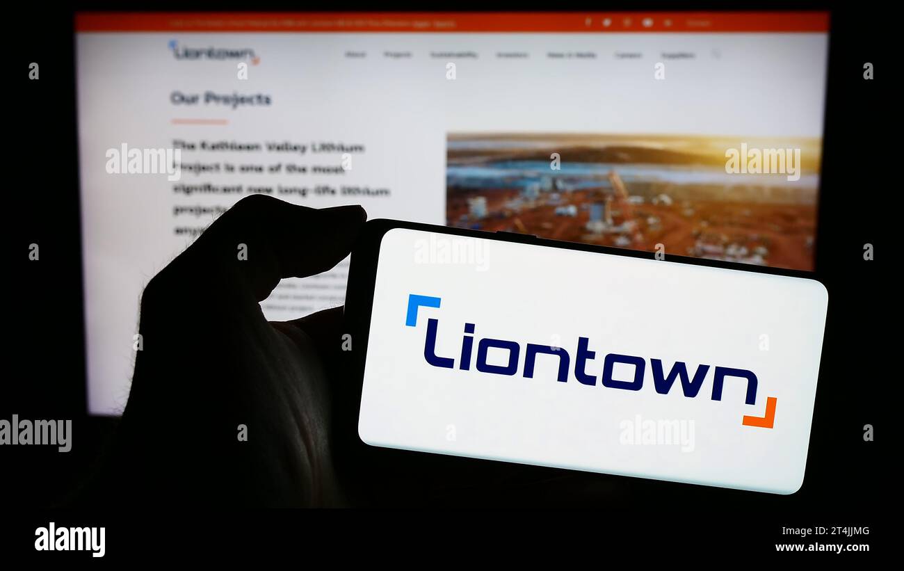 Persona che possiede uno smartphone con il logo della società mineraria australiana Liontown Resources Limited davanti al sito Web. Concentrarsi sul display del telefono. Foto Stock