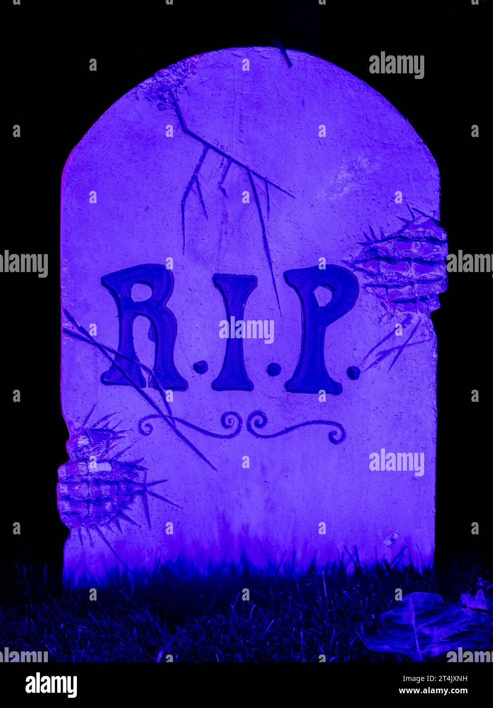 Halloween Blue Purple illuminato Tombstone con il cartello R.I.P. che si illumina al buio Foto Stock