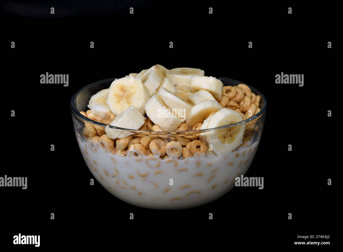Cereali per colazione con banana tagliata in una ciotola di vetro. Foto Stock