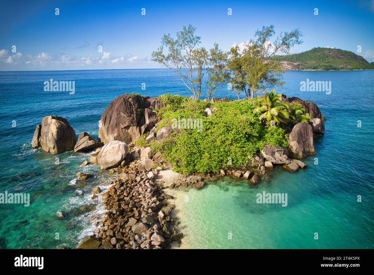 Drone dell'isola di Therese all'orizzonte dietro rocce e alberi di granito, Mahe Seychelles Foto Stock