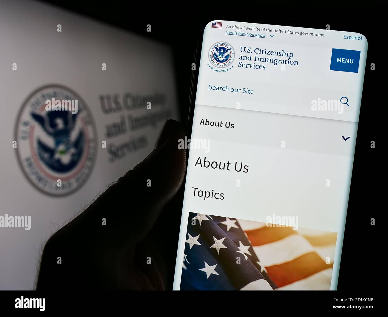 Persona in possesso di smartphone con sito Web dell'agenzia statunitense Citizenship and Immigration Services (USCIS) con sigillo. Concentrarsi sul centro del display del telefono. Foto Stock