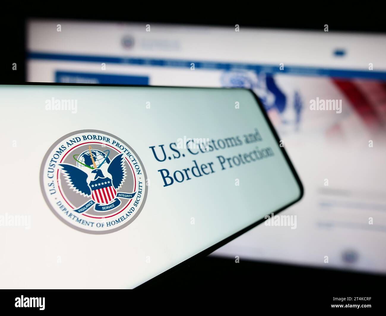 Smartphone con sigillo dell'agenzia United States Customs and Border Protection (CBP) davanti al sito Web. Mettere a fuoco sul lato sinistro del display del telefono. Foto Stock