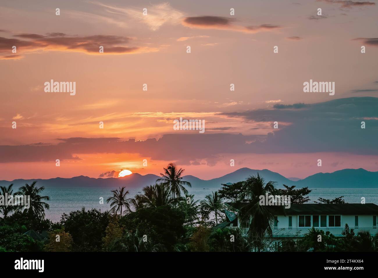 Tramonto panoramico con luce dorata rosa. Half Sun si è nascosto dietro le montagne. Vista ravvicinata su palme, mare e montagne all'orizzonte. Ao Nang, Thailandia Foto Stock