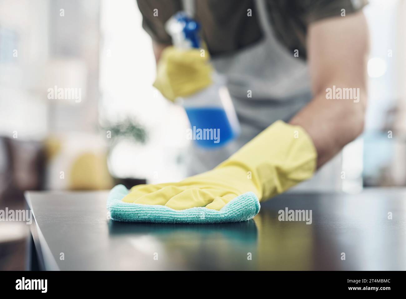 Eliminare lo sporco con un po' di grasso a gomito. un uomo irriconoscibile che disinfetta un tavolo a casa. Foto Stock