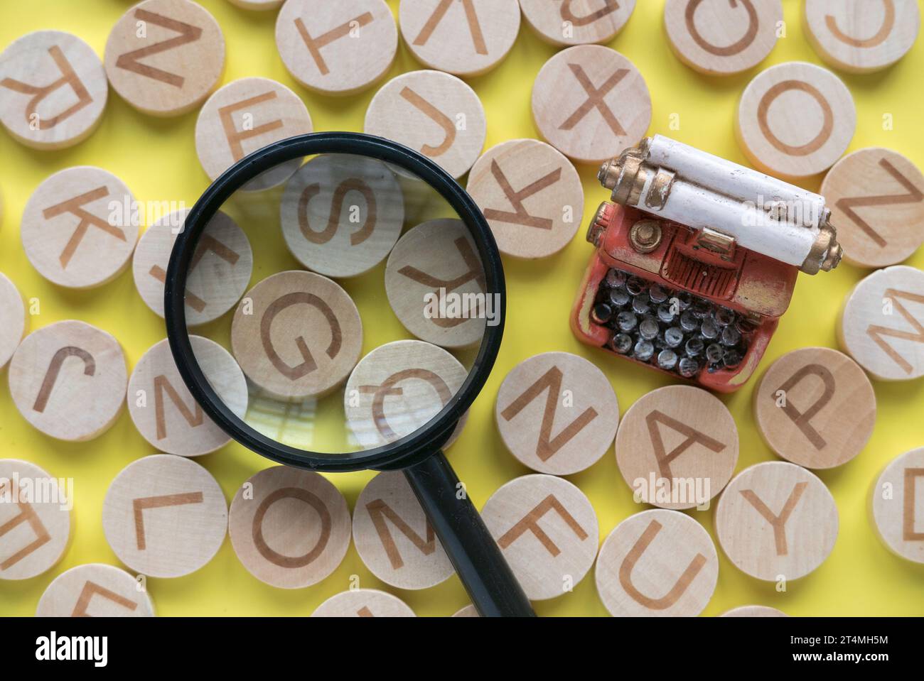 Concetto di apprendimento dell'inglese, ricerca di parole e informazioni. Lettera alfabetica inglese e lente di ingrandimento su sfondo giallo. Foto Stock