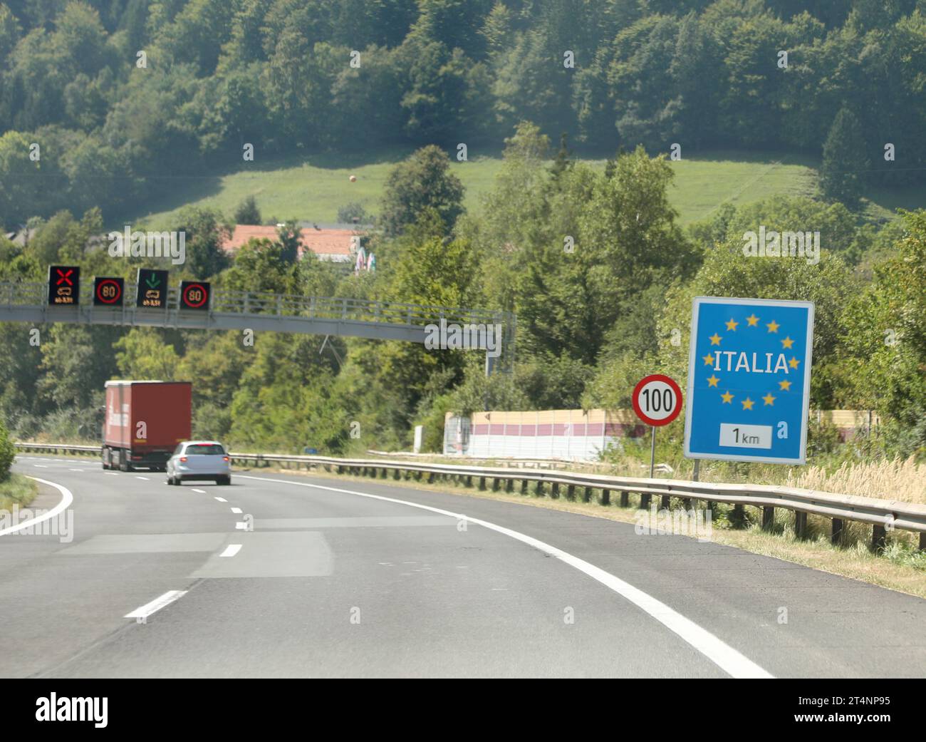Grande cartello stradale con il testo ITALIA e stelle europee gialle vicino al confine italiano in montagna Foto Stock
