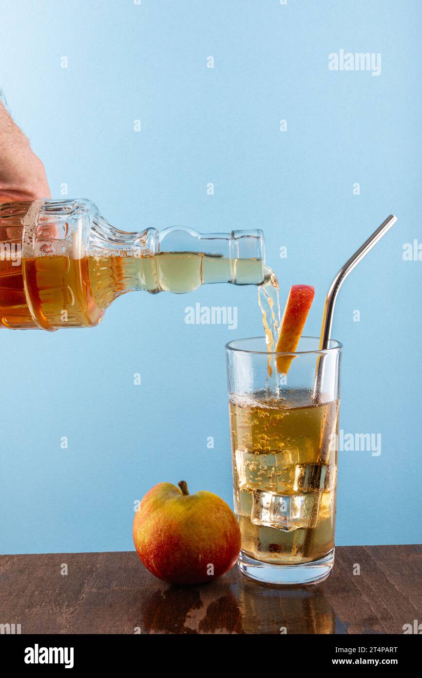 versare il succo di mela in un bicchiere su sfondo blu con spazio per la copia Foto Stock