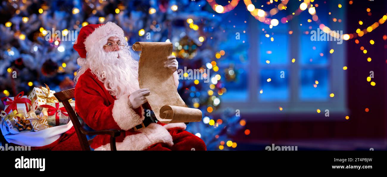 Babbo Natale nella sua casa leggendo la lista dei desideri di notte - albero di Natale e finestra con luci bokeh astratte sfocate Foto Stock