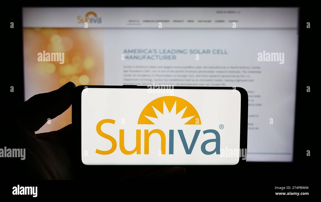 Persona che possiede uno smartphone con il logo della società statunitense di fotovoltaica Suniva Inc. Davanti al sito Web. Concentrarsi sul display del telefono. Foto Stock