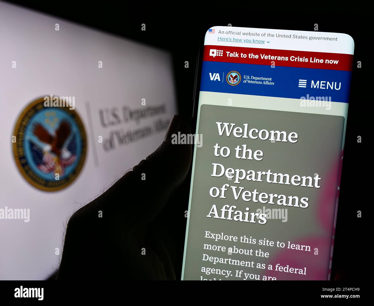 Persona che tiene il cellulare con la pagina web del Dipartimento dei Veterani degli Stati Uniti (va) davanti al sigillo. Concentrarsi sul centro del display del telefono. Foto Stock