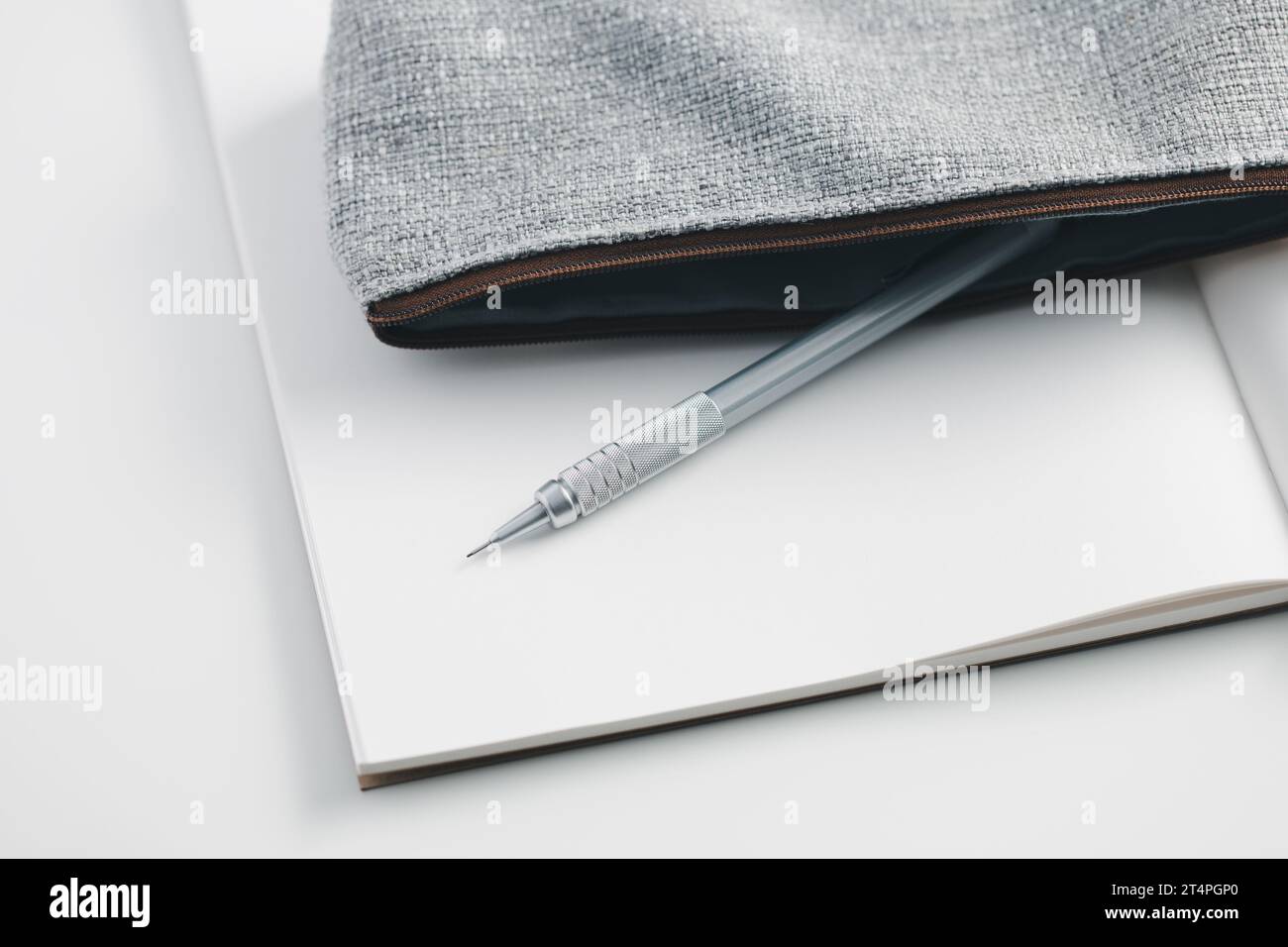 Matita meccanica in astuccio posizionato su un notebook bianco. Foto Stock