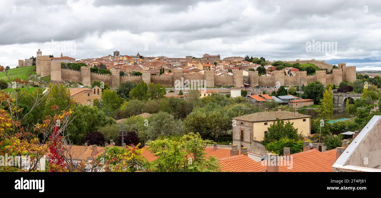 Panorama ad alta risoluzione della città di Avila con le famose mura medievali della città con merlature, architettura gotica e vegetazione verde intorno, Spagna Foto Stock