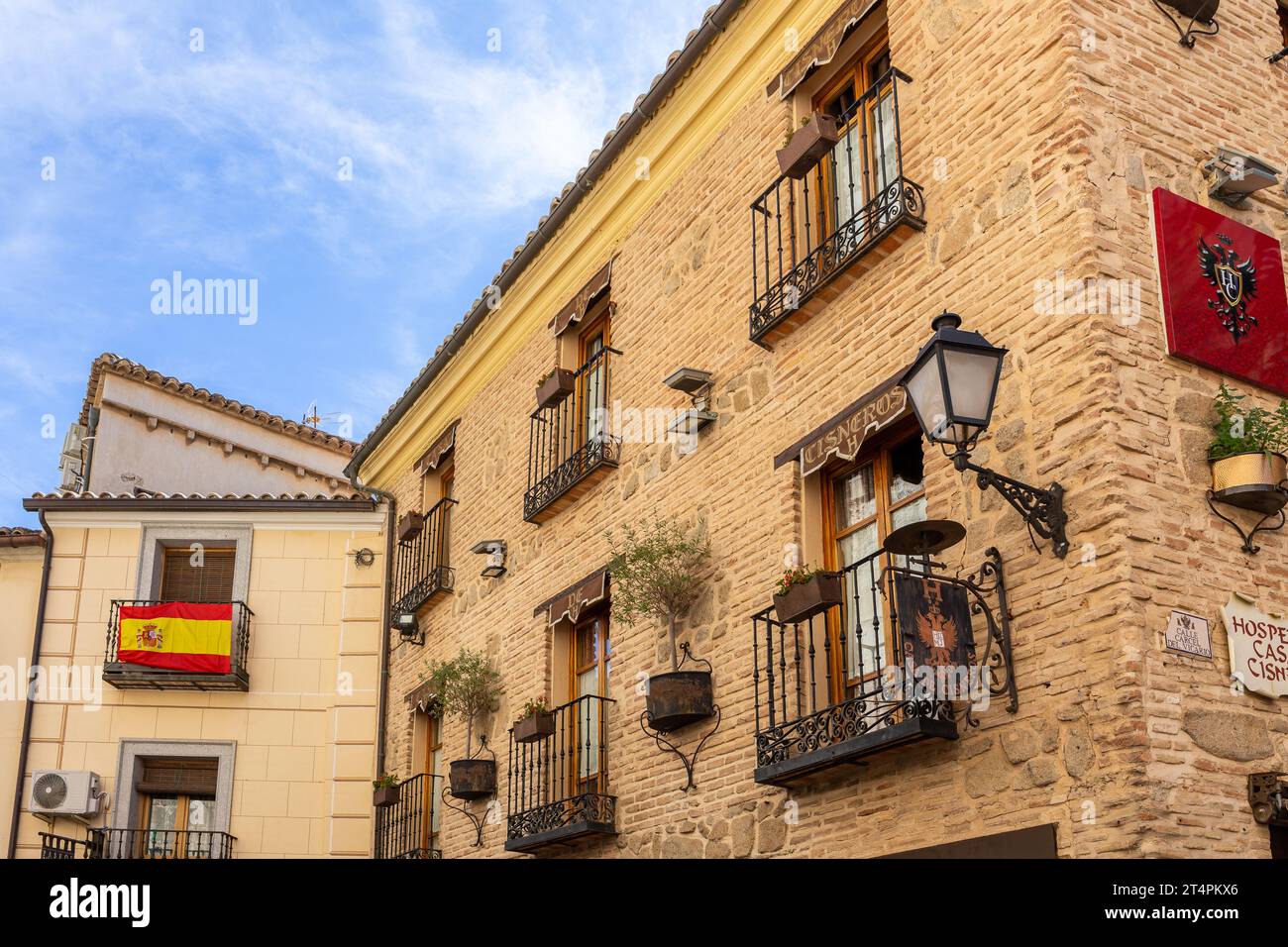 Toledo, Spagna, 08.10.21. Facciate di edifici residenziali a Toledo, Spagna, con balconi tradizionali con vasi di fiori e bandiera nazionale spagnola. Foto Stock