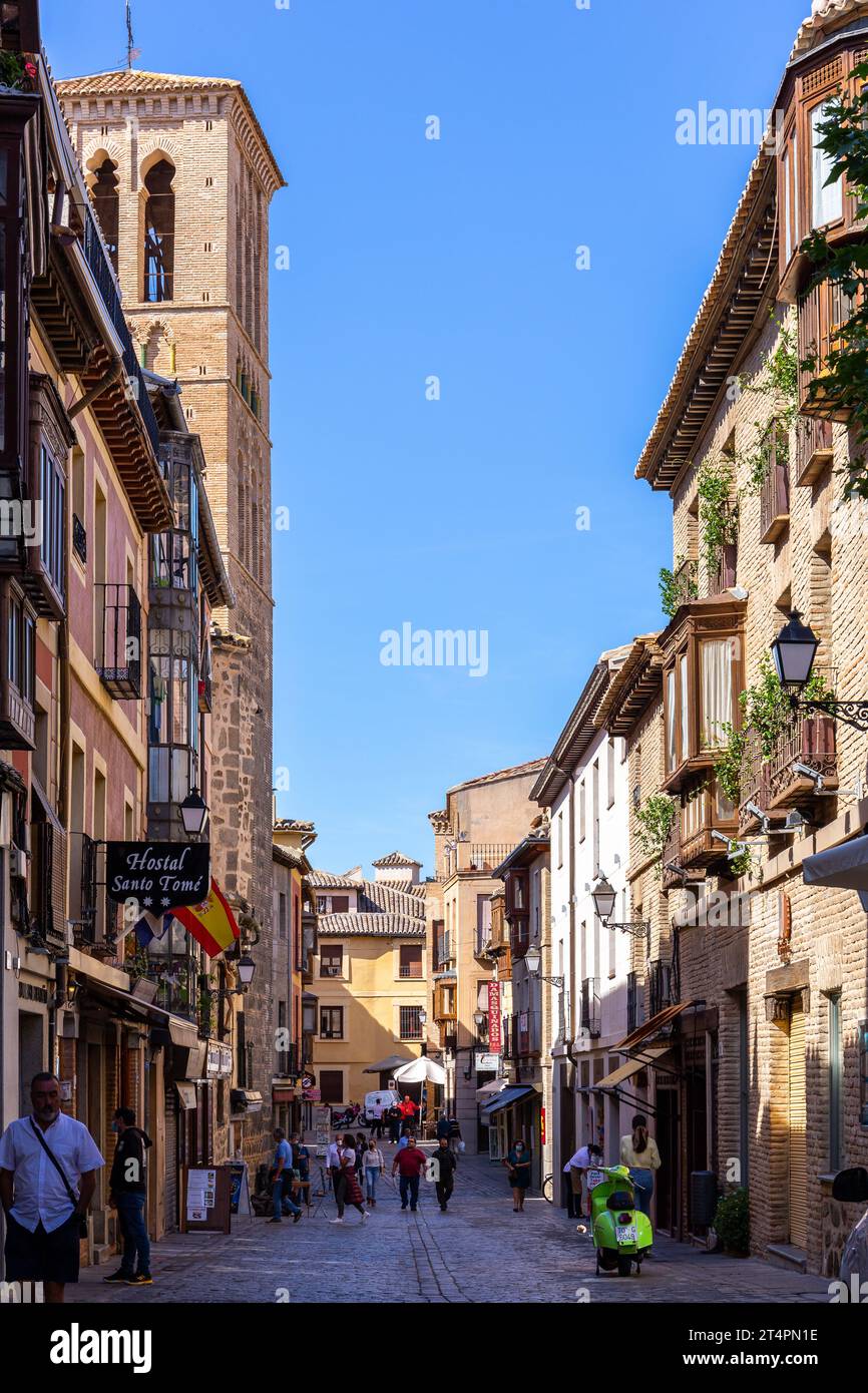 Toledo, Spagna, 08.10.21. Calle de Santo Tome, stretta strada medievale acciottolata con negozi, hotel, ristoranti, balconi tradizionali e chiesa. Foto Stock