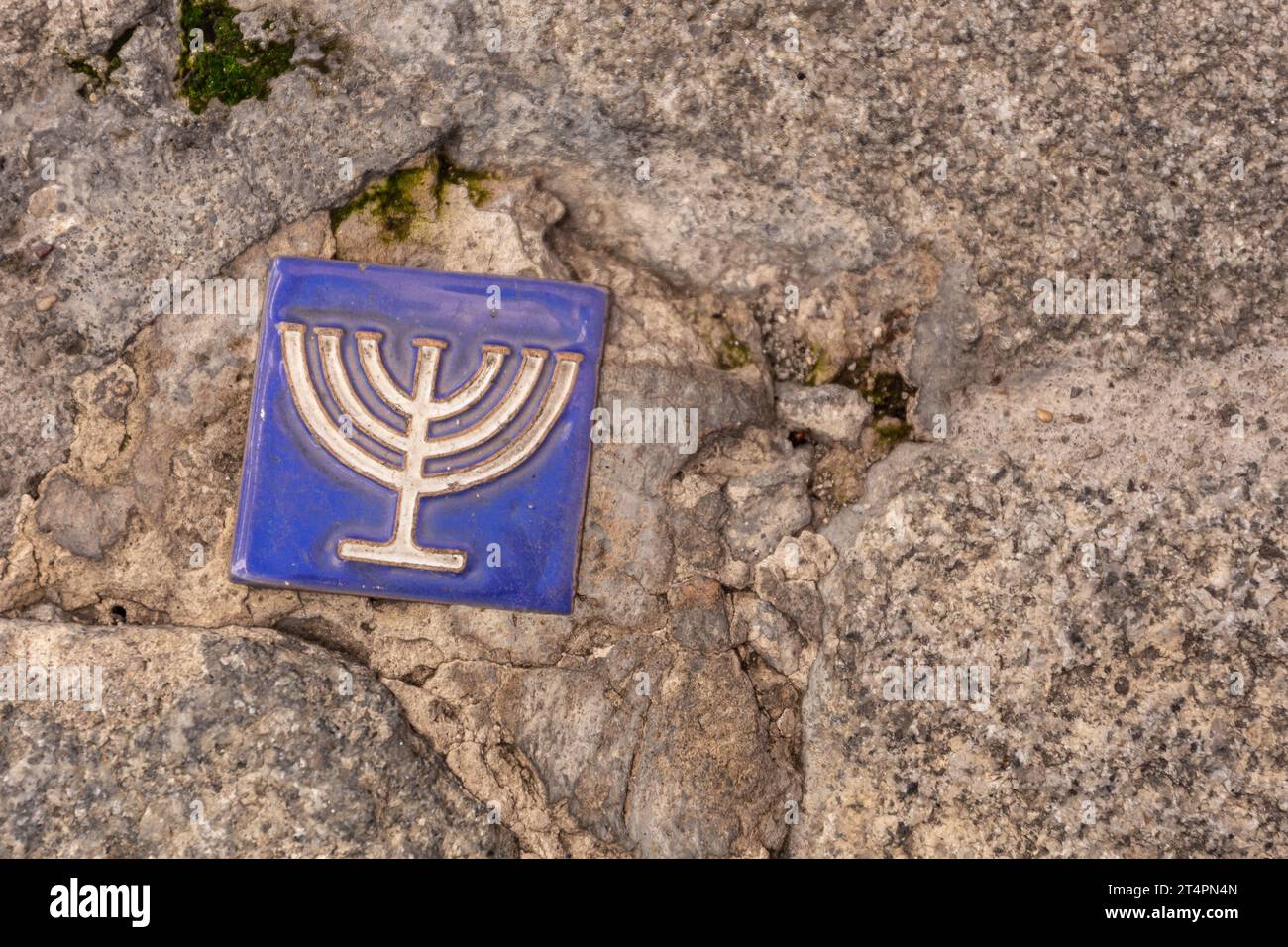 Piccola piastrella blu con il simbolo della menorah incorporata nel marciapiede dell'ex quartiere ebraico, Toledo, Spagna, spazio copia. Foto Stock