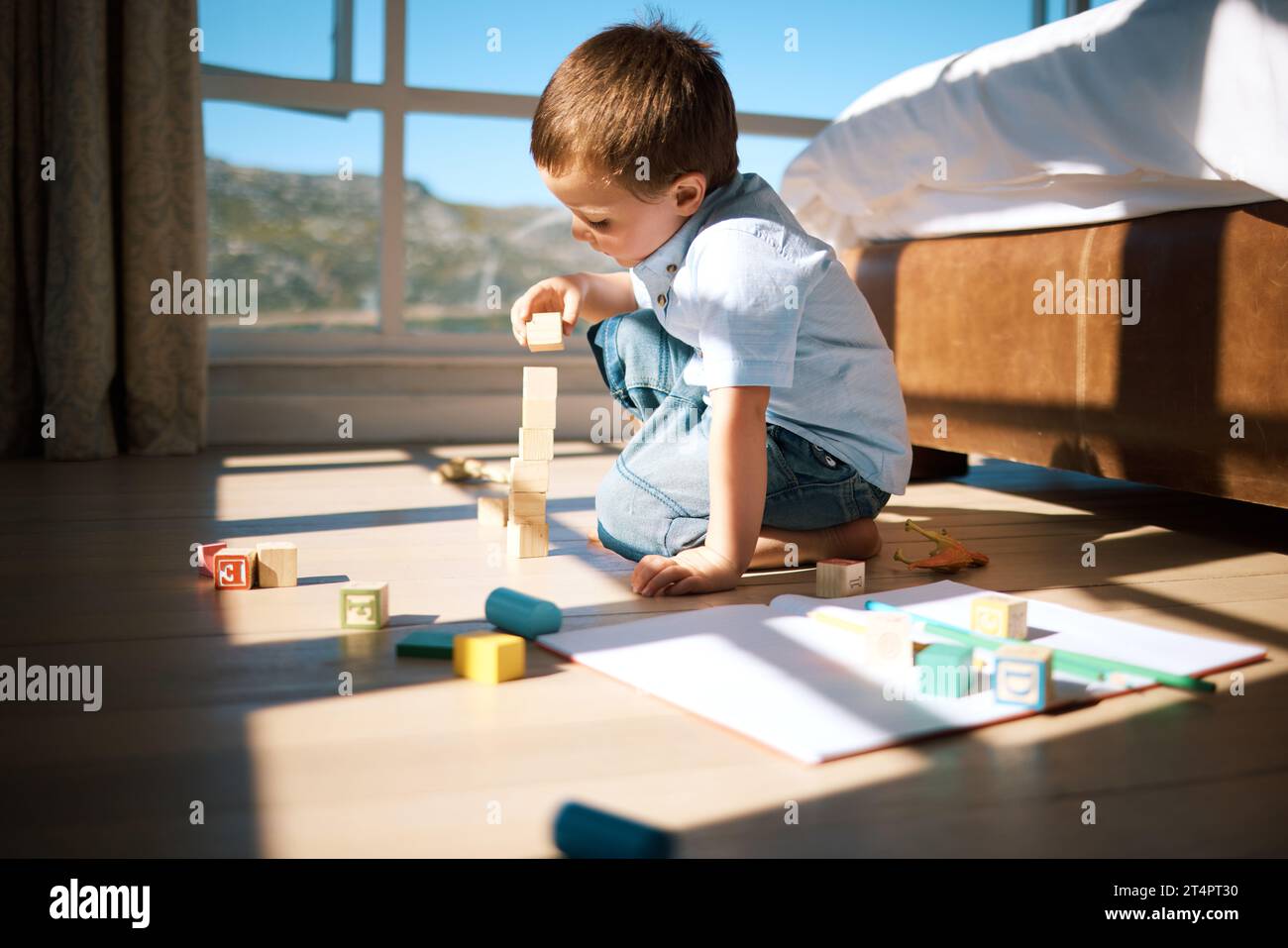 Un bambino che costruisce una torre con blocchi di legno. Adorabili giocattoli caucasici impilabili per bambini, sviluppando abilità motorie fini e coordinazione occhio-mano Foto Stock