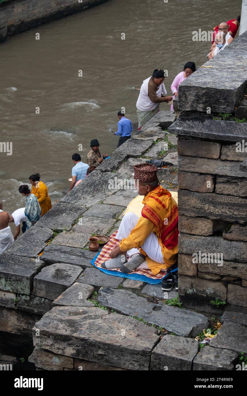 Kathmandu, Nepal: Guru indù in attesa che una famiglia prepari regali per i morti al tempio Pashupatinath, famoso tempio indù dedicato a Shiva Foto Stock