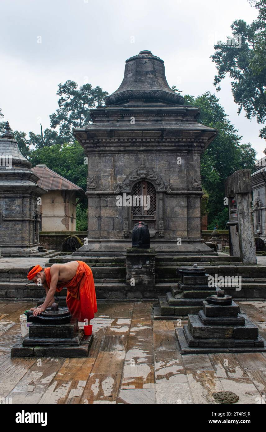 Kathmandu, Nepal: Monaco indù che pulisce gli altari dopo il sacrificio degli animali e le cerimonie di preghiera, cerimonia di cremazione al Tempio di Pashupatinath, tempio indù Foto Stock