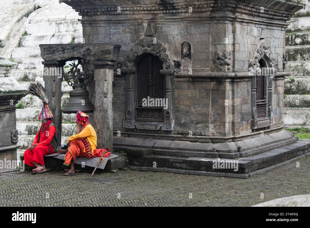 Kathmandu, Nepal: Guru indù in attesa che una famiglia prepari regali per i morti al tempio Pashupatinath, famoso tempio indù dedicato a Shiva Foto Stock