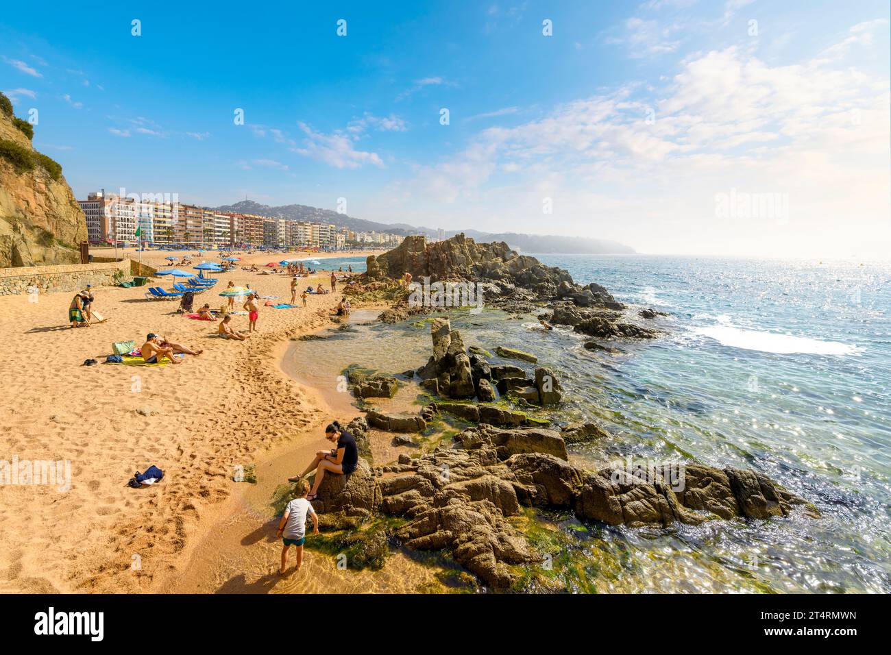 Spagnoli e turisti si godono una giornata estiva sull'ampia spiaggia sabbiosa di Playa grande nella località turistica spagnola di Lloret de Mar, sulla costa della Costa Brava. Foto Stock