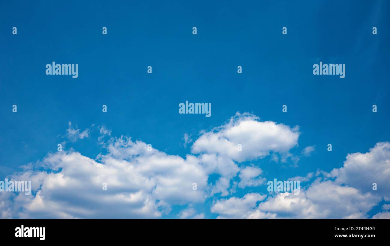 La tela del giorno è dipinta con un tranquillo e sereno cielo blu, adornata da soffici nuvole di cumulus bianche, che offrono un'atmosfera tranquilla. Foto Stock