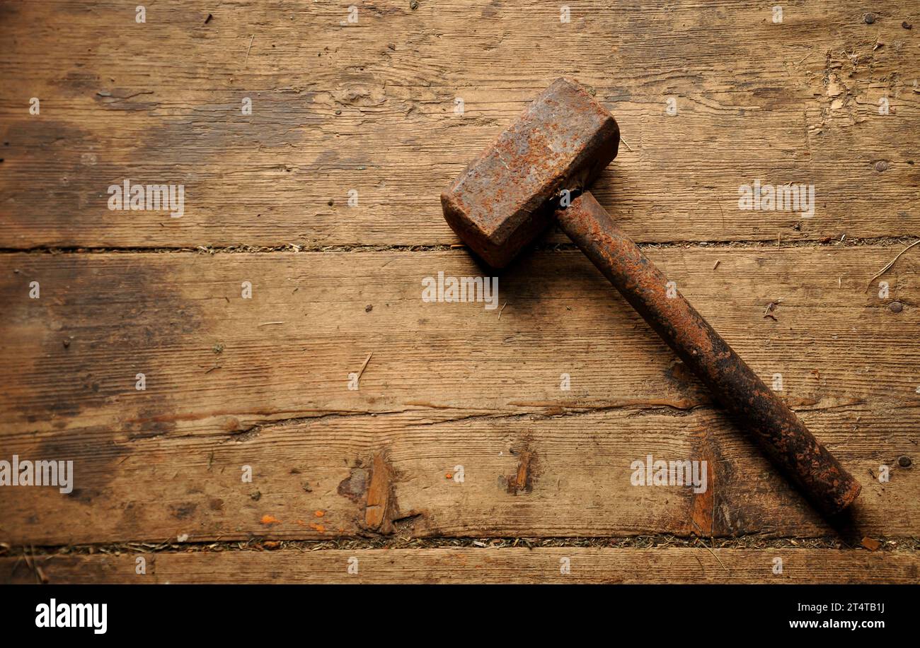 Martello di metallo arrugginito molto vecchio su un pavimento di legno antico e malandato. Sfondo semplice. Copia spazio Foto Stock