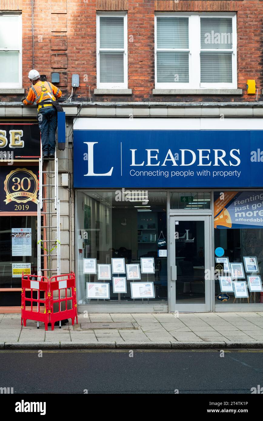 ingegnere che lavora su scala per la comunicazione di cablaggio leader della scatola di comunicazione slogan di un negozio di agenti immobiliari che collega le persone con la proprietà southsea inghilterra regno unito Foto Stock