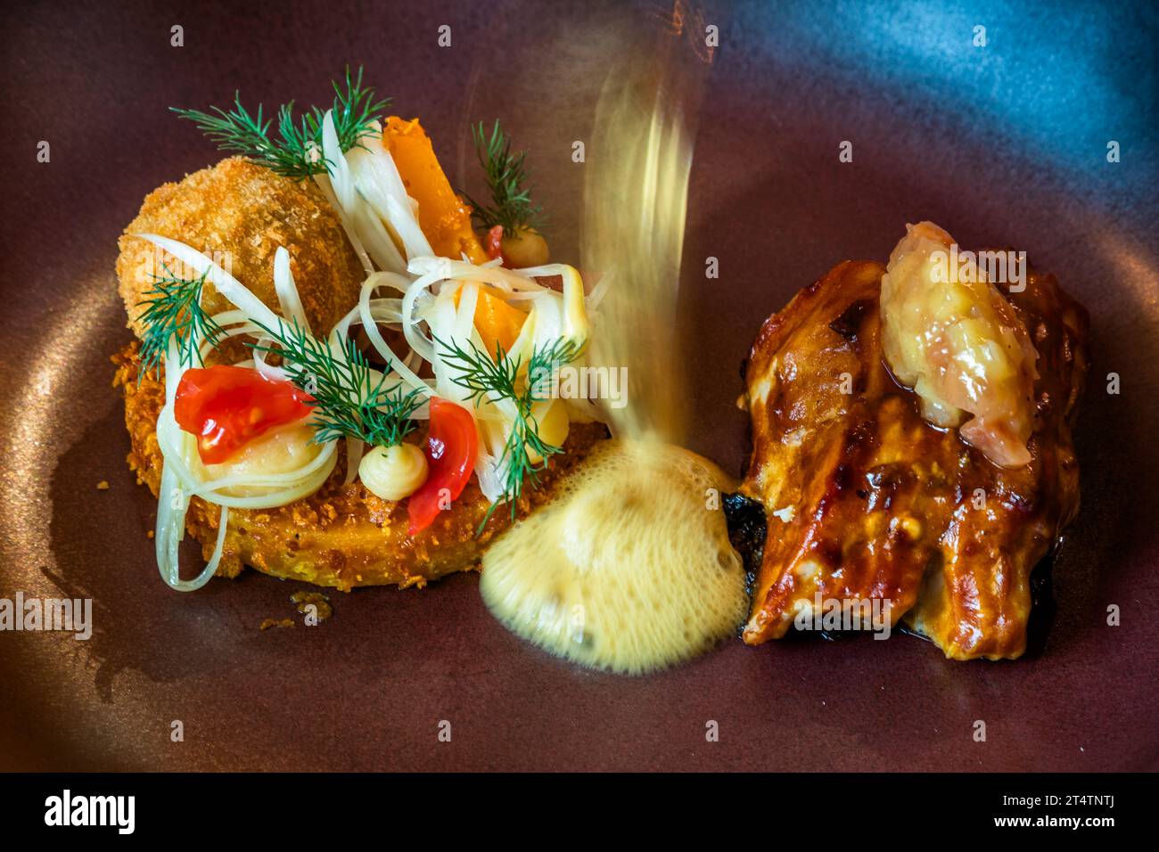 Una salsa schiumosa di zucca viene versata su un piatto di filetto di carpa argentata glassato con una vernice di testa di pesce caramellata, al ristorante Holzfellas. Wiesau (VGem), Bavaria, Germania. Foto Stock