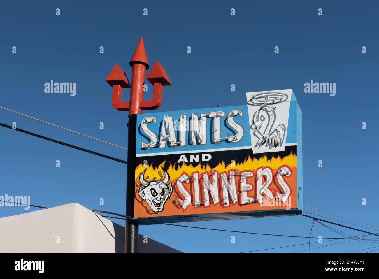 Insegna al neon dai colori vivaci con tridente rosso per Saints and Sinners, negozio di liquori fondato nel 1963, Espanola, New Mexico, Stati Uniti, Stati Uniti. Foto Stock