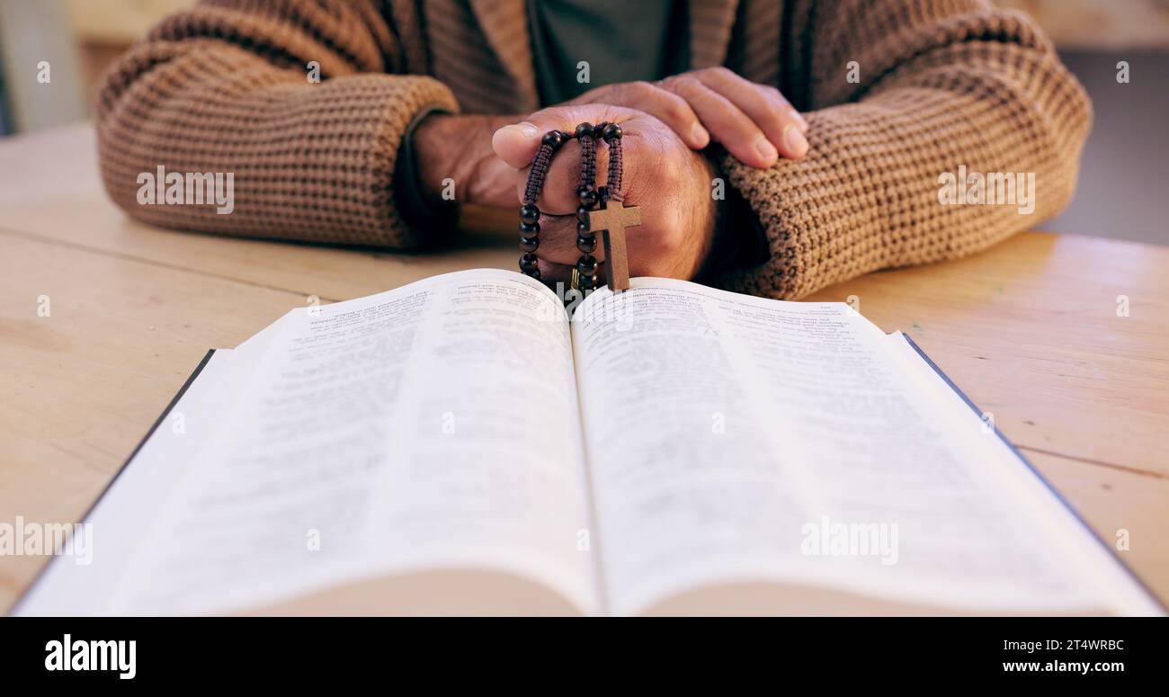 Mani, rosario e bibbia con primo piano per la fede, la pace e la speranza alla scrivania, a casa o in preghiera per il culto. Persona, croce e gioielli per la religione Foto Stock