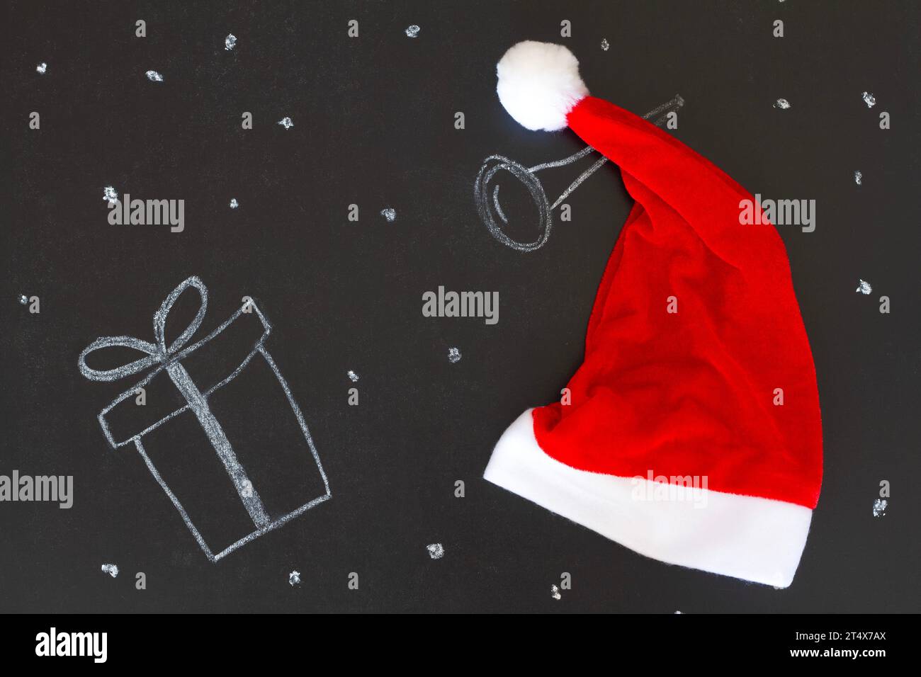 Regalo disegnato con gesso sulla lavagna con cappello di Babbo Natale, sfondo natalizio creativo Foto Stock