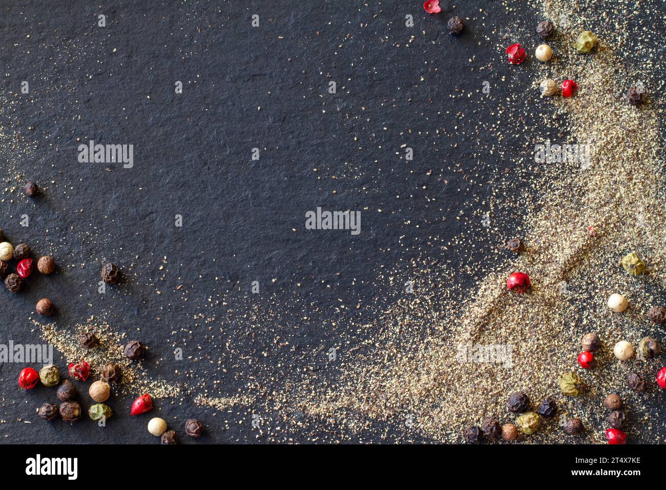Pepe macinato e grani di pepe colorato su sfondo nero, spazio copia Foto Stock