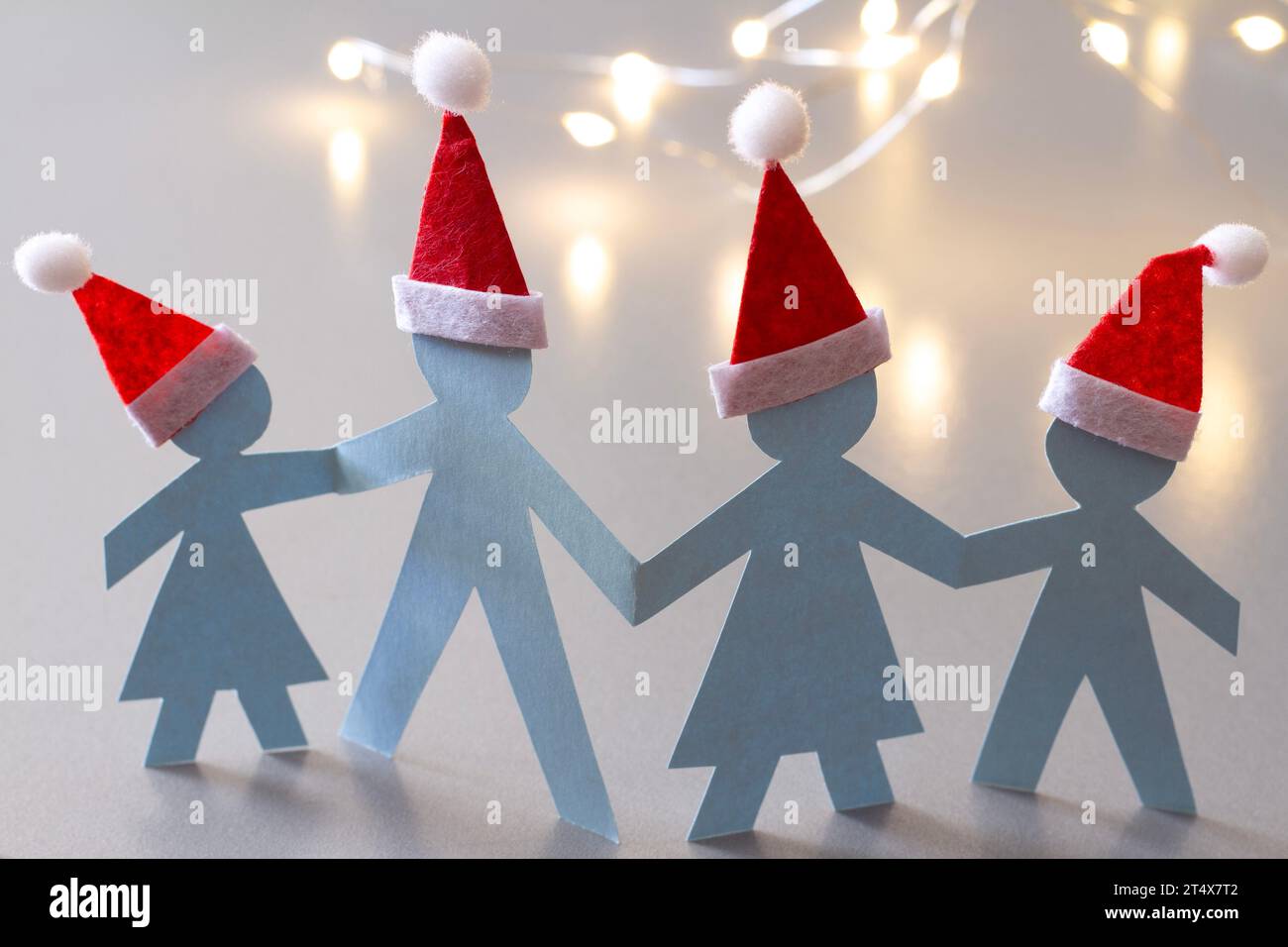 Famiglia di persone di carta che si tengono per mano nei cappelli di Babbo Natale, concetto di famiglia di natale Foto Stock