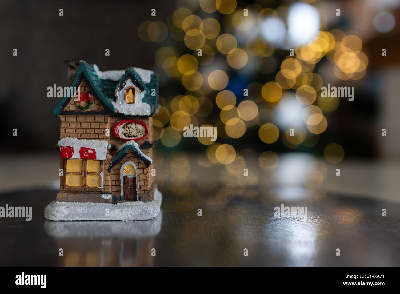 Felice anno nuovo e buon Natale - casa souvenir su uno sfondo di ghirlande gialle, bokeh. E' tempo di cambiare, auguri per il nuovo anno. Foto Stock