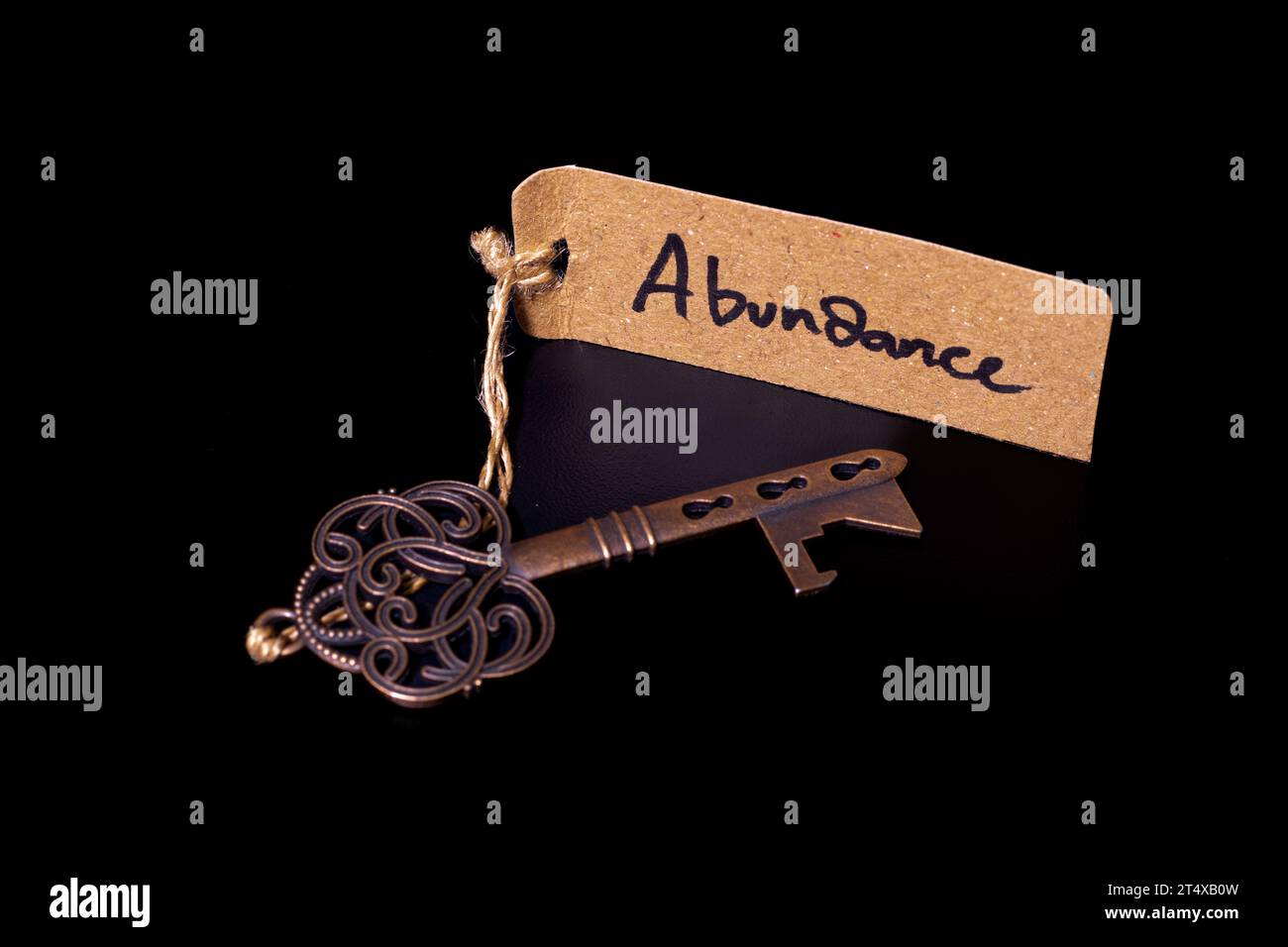 Key to Abundant Life Concept - Old key con abundance tag isolato su sfondo nero Foto Stock