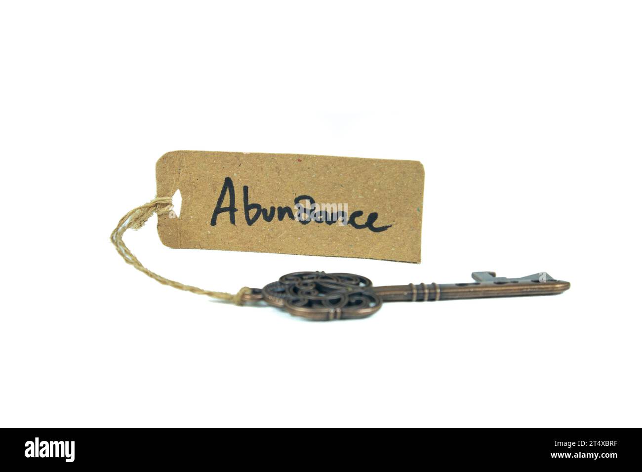 Key to Abundant Life Concept - Old key con abundance tag isolato su sfondo bianco Foto Stock