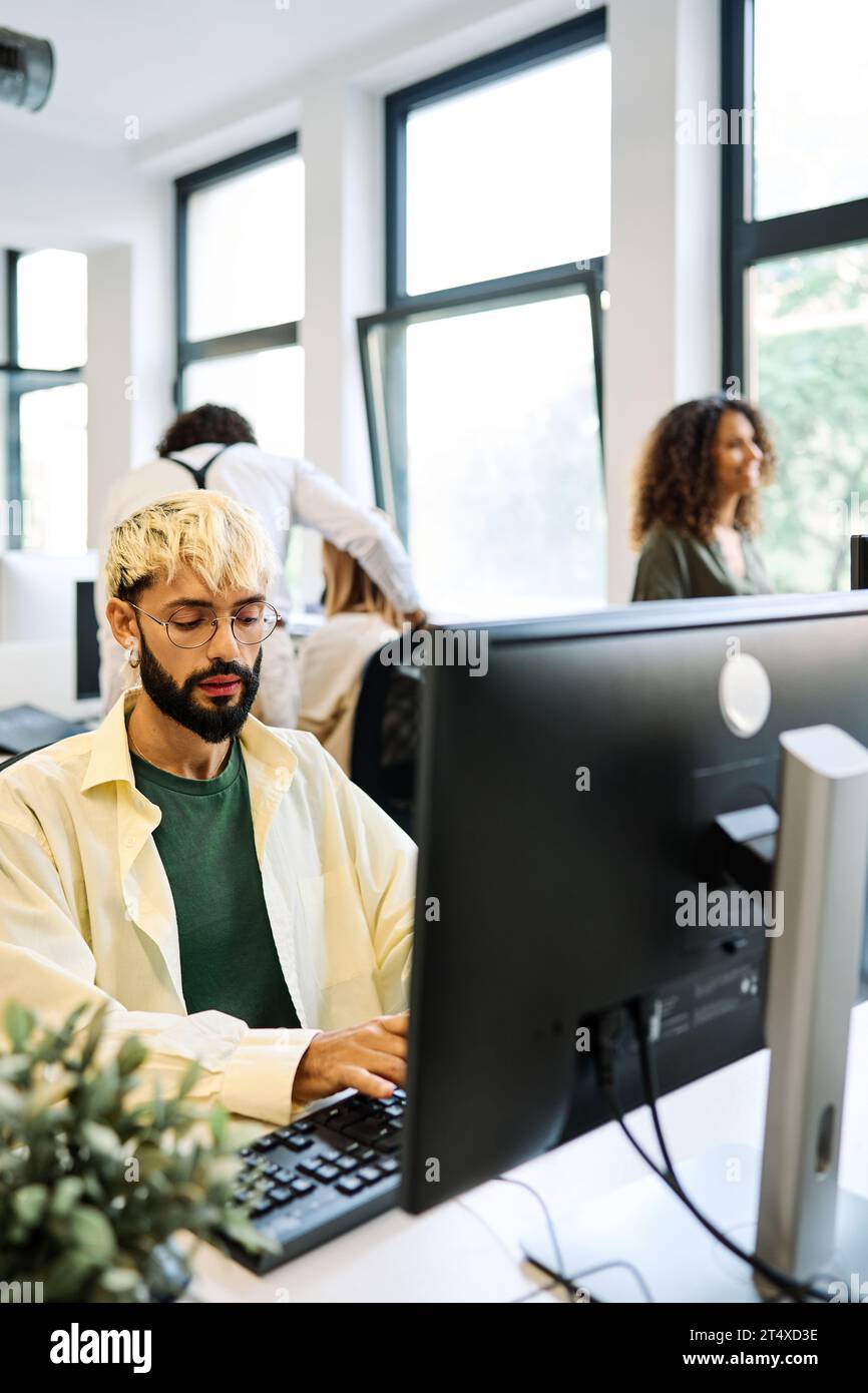 Un giovane alternativo che usa il computer in un coworking Foto Stock