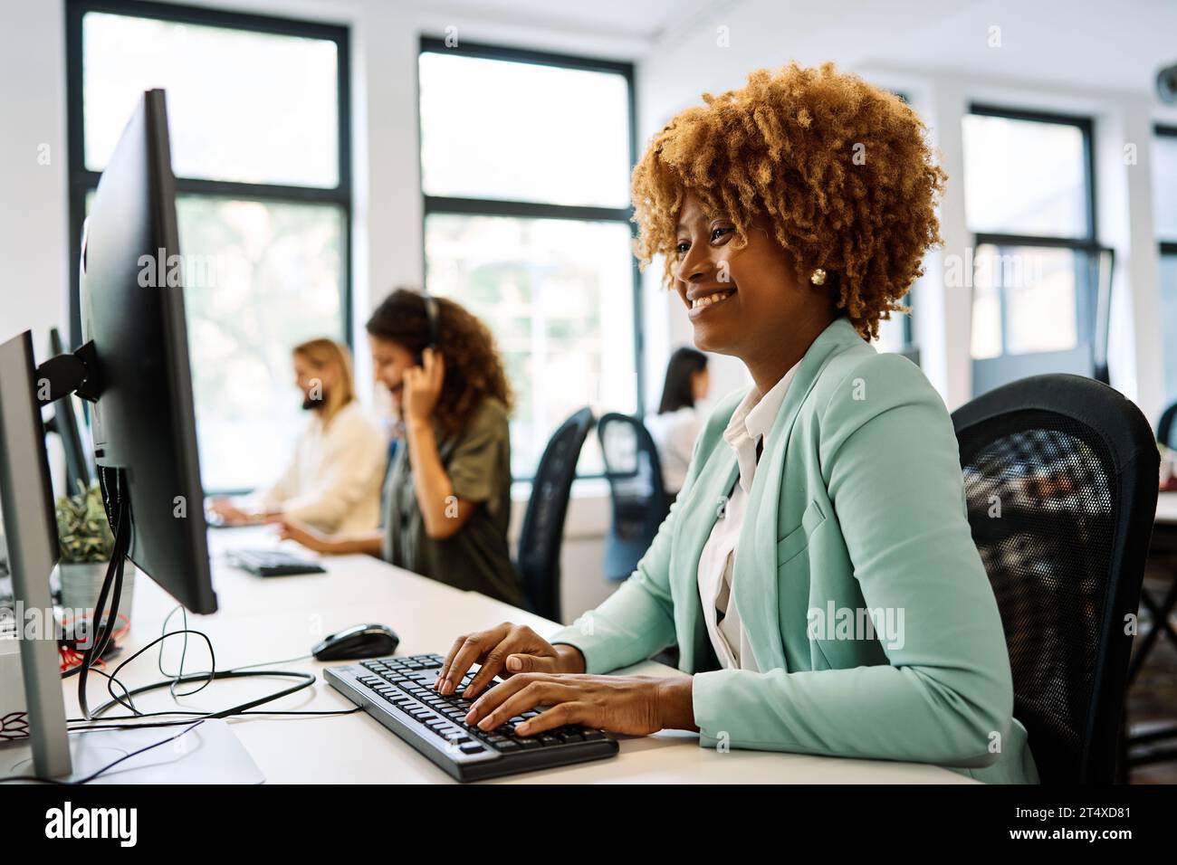 Donna africana che usa un computer seduto in un ufficio di coworking Foto Stock
