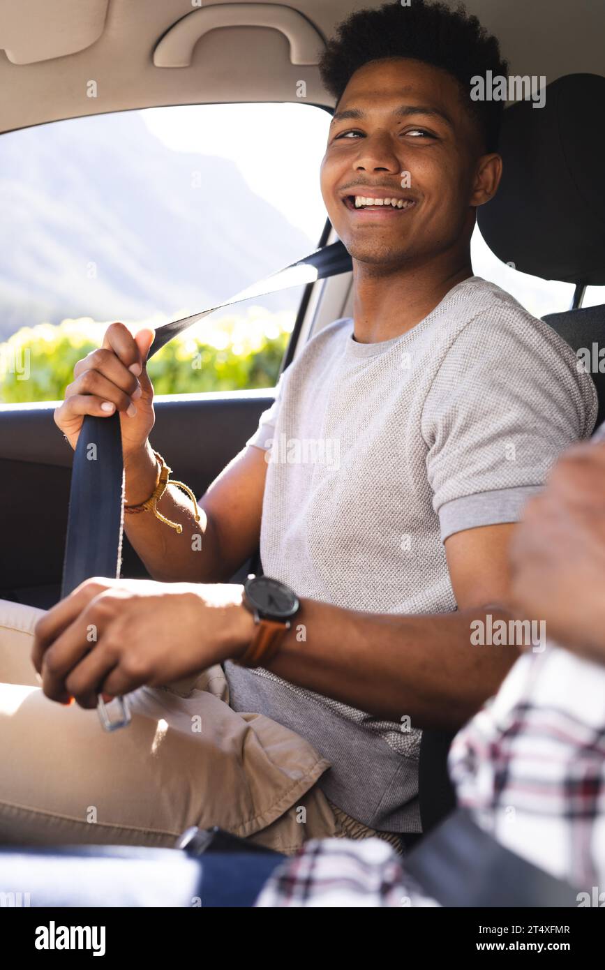 Sorridente figlio adulto afroamericano in auto con padre, figlio che indossa la cintura di sicurezza prima di guidare Foto Stock