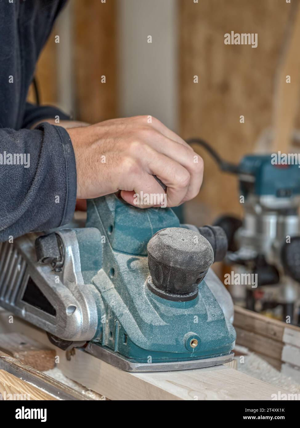 Carpentiere che pialla una tavola con una pialla manuale elettrica Foto Stock