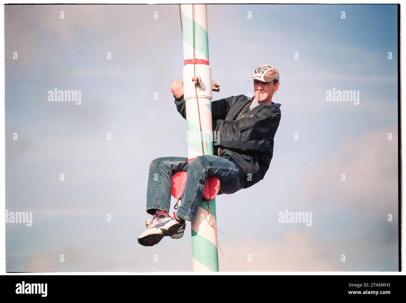 FAN POP, ARRAMPICATA, VISTA MIGLIORE, BARRY ISLAND, 1996: un uomo con una sigaretta su un lampione per avere una vista migliore mentre un'enorme folla si riunisce sulla spiaggia vicino al Barry Island Pleasure Park per un Red Dragon FM Pop Concert con dozzine di artisti pop a Barry, Galles, Regno Unito, il 27 maggio 1996. Foto: Rob Watkins Foto Stock