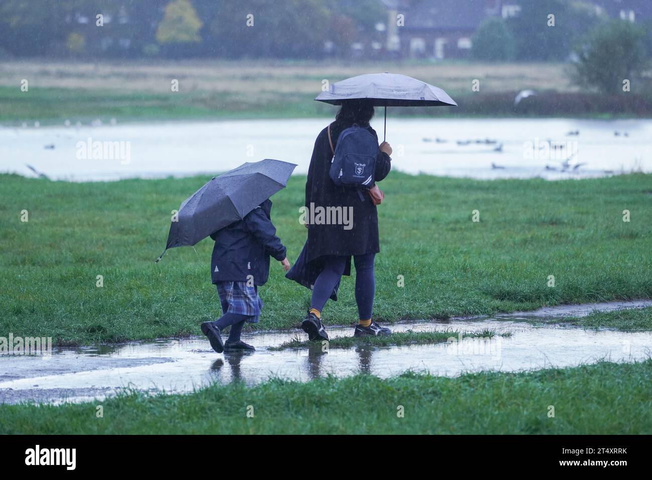 Londra, Regno Unito. 2 novembre 2023. Una passeggiata per genitori e bambini con ombrelloni su un acquascivolo di Wimbledon Common, a sud-ovest di Londra questa mattina. Il Met Office nel sud dell'Inghilterra ha emesso un avviso color ambra in caso di condizioni meteorologiche avverse per il vento che potrebbe raggiungere i 104 km/h. Credit amer ghazzal/Alamy Live News Foto Stock