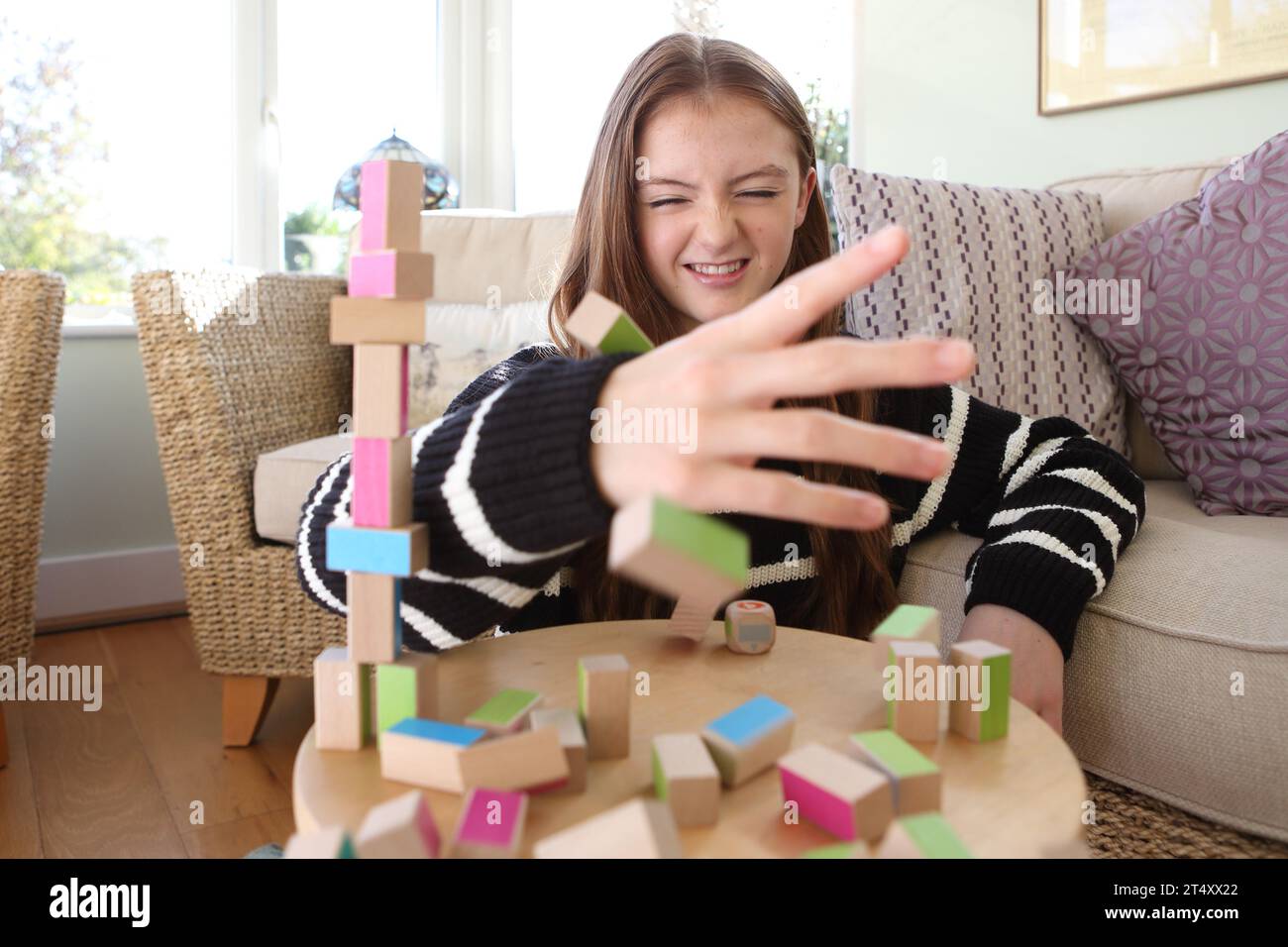 Adolescente che costruisce un muro di blocchi di legno e costruisce una torre Foto Stock