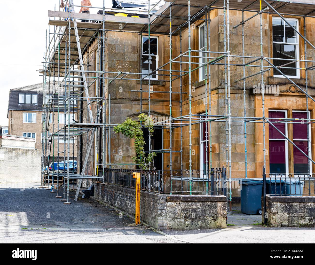 Grande casa in pietra completamente impalcata o piccola impresa in fase di ristrutturazione e riparazione con accesso laterale del veicolo Foto Stock